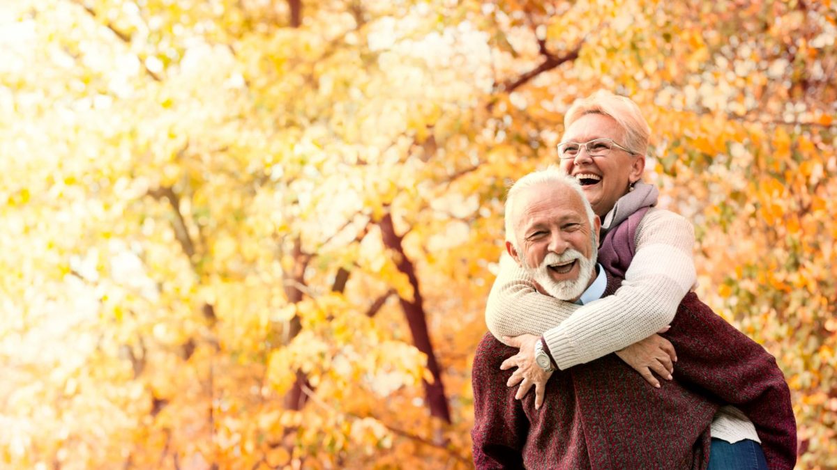 Older couple walking together in the woods considering Medicare options