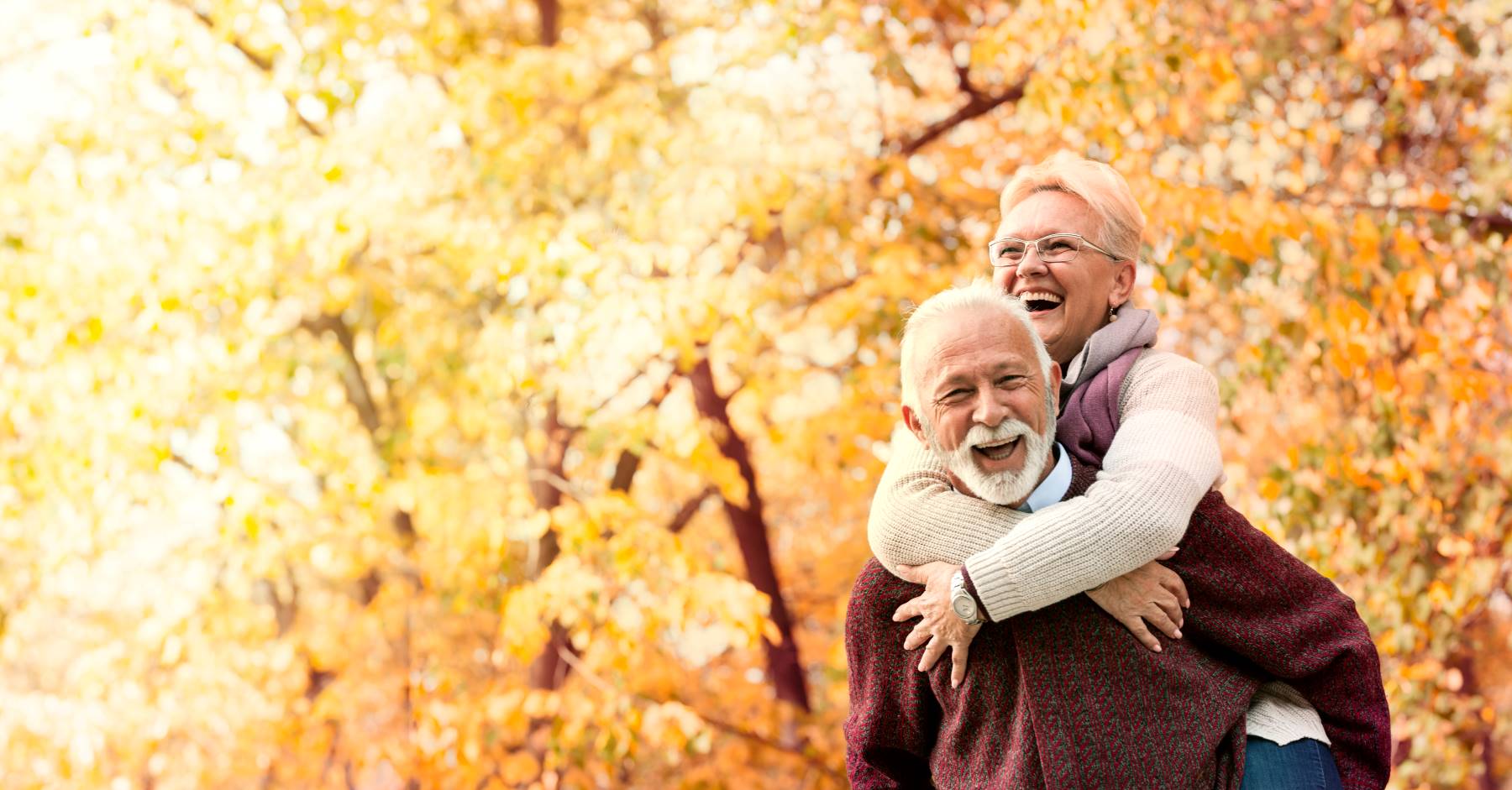 Older couple walking together in the woods considering Medicare options